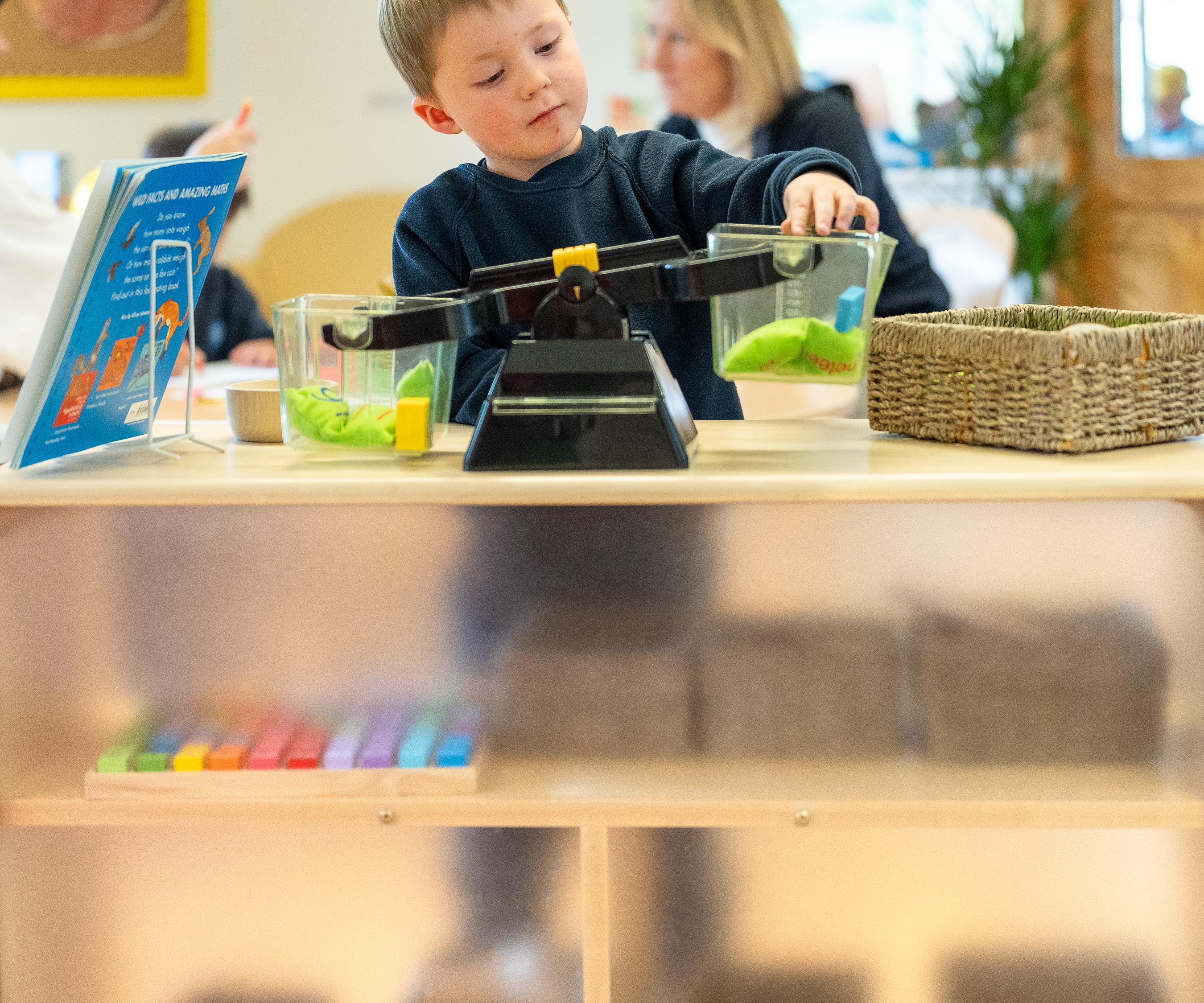 A boy working at a scale on the top of a translucent-backed shelf