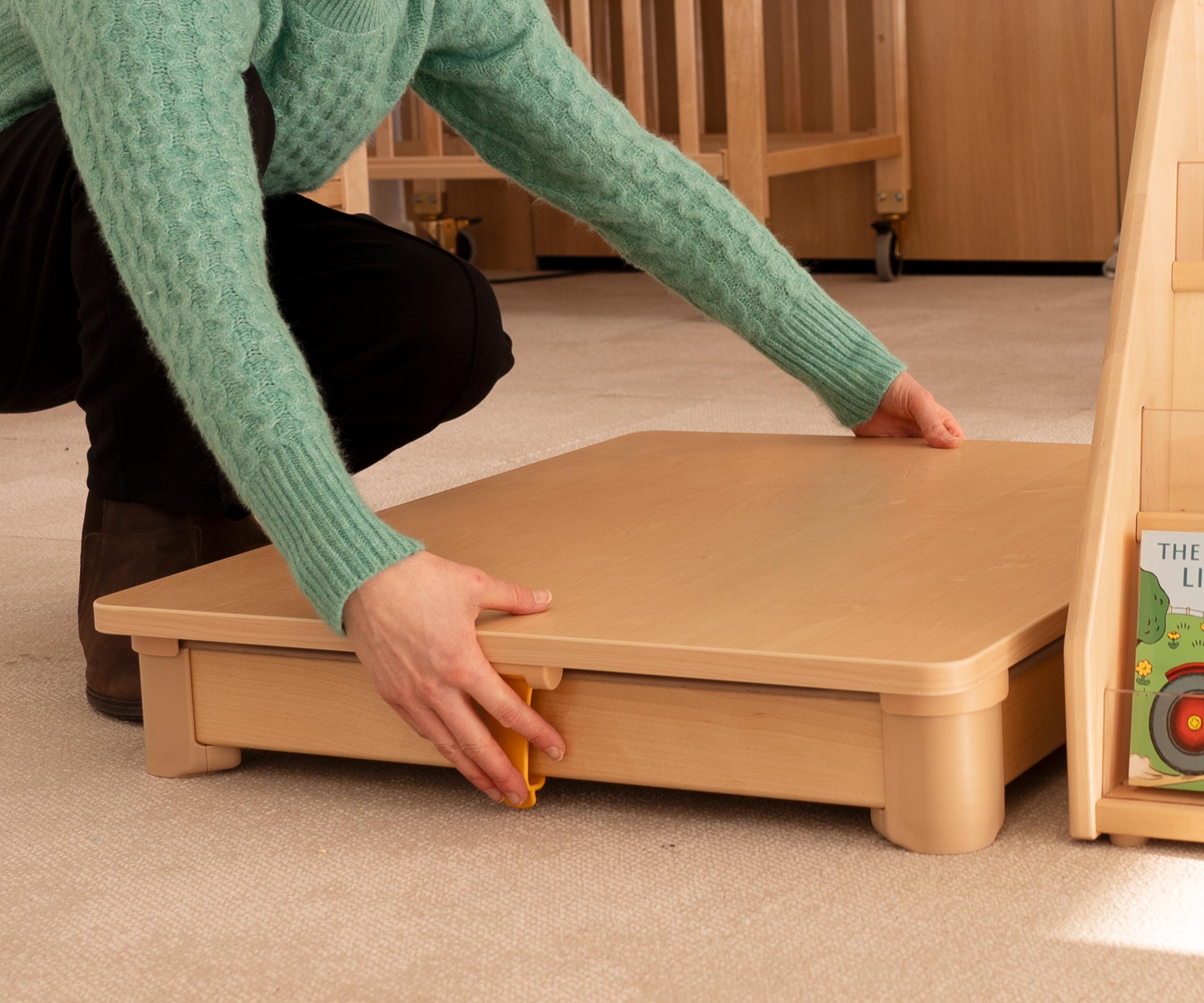 Closeup of an educator clipping the wooden lid onto an Activity floor tray