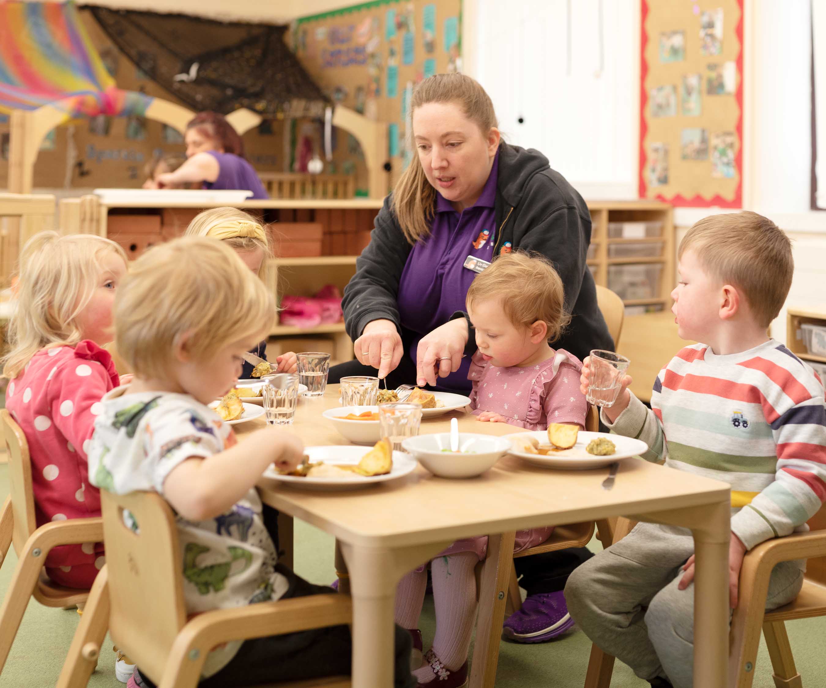 Five nursery aged children eating lunch together at a table