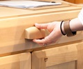 The hand of an adult reaching for the handle of the drawer of a teacher standing desk