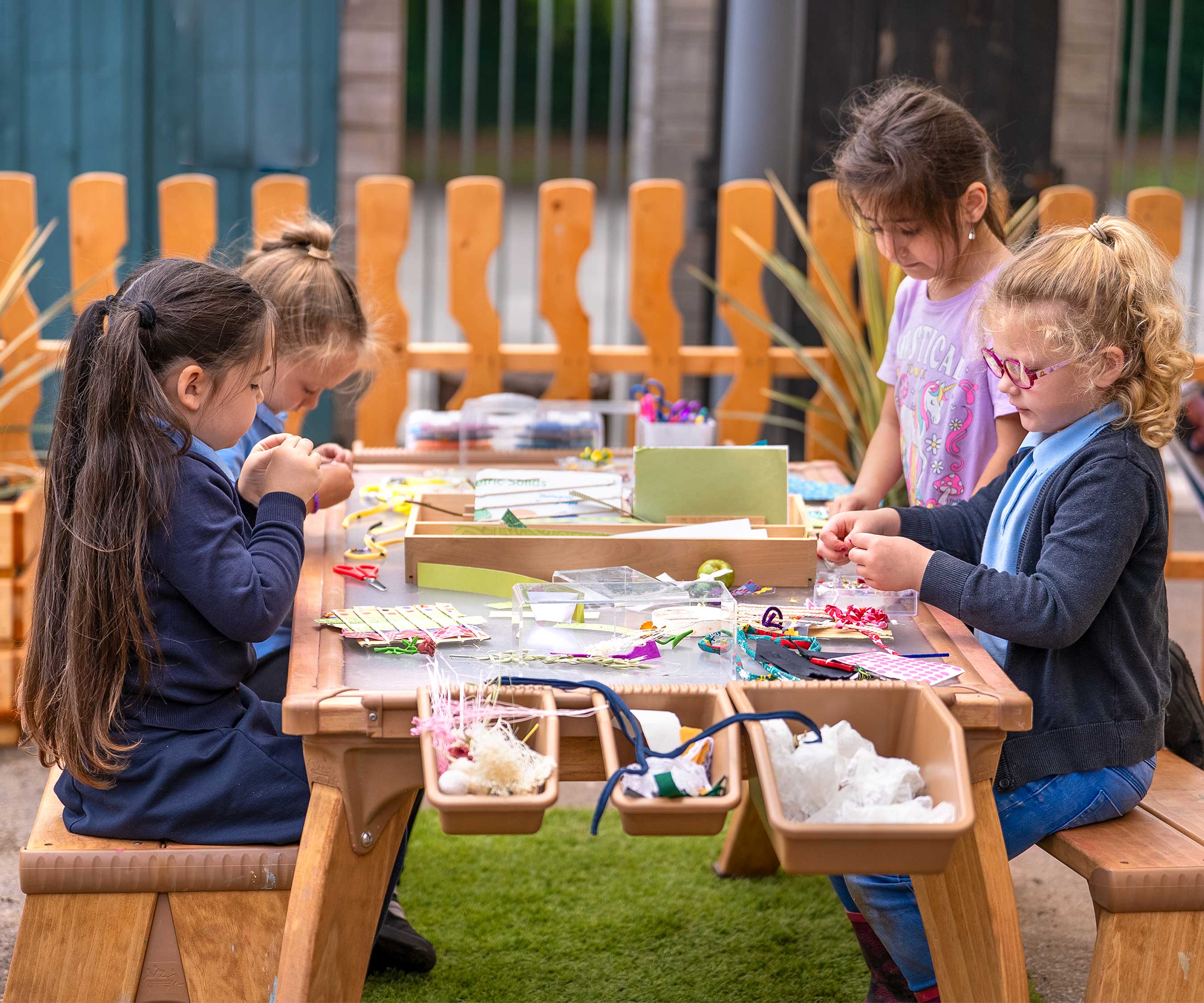 Year one students doing sewing projects at an outdoor art table.