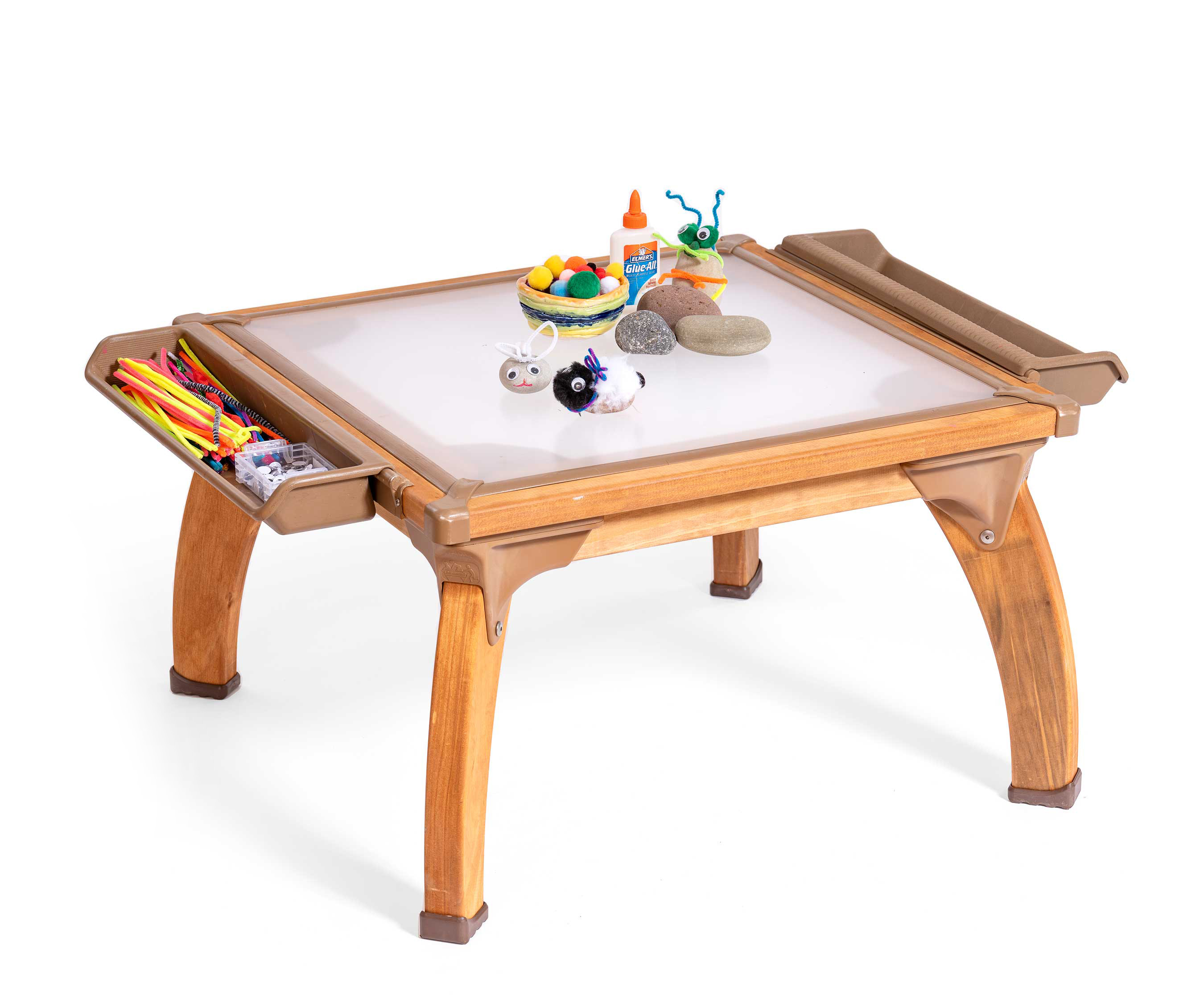 A translucent topped art table with pebbles, glue, and paint layed out for an art project.