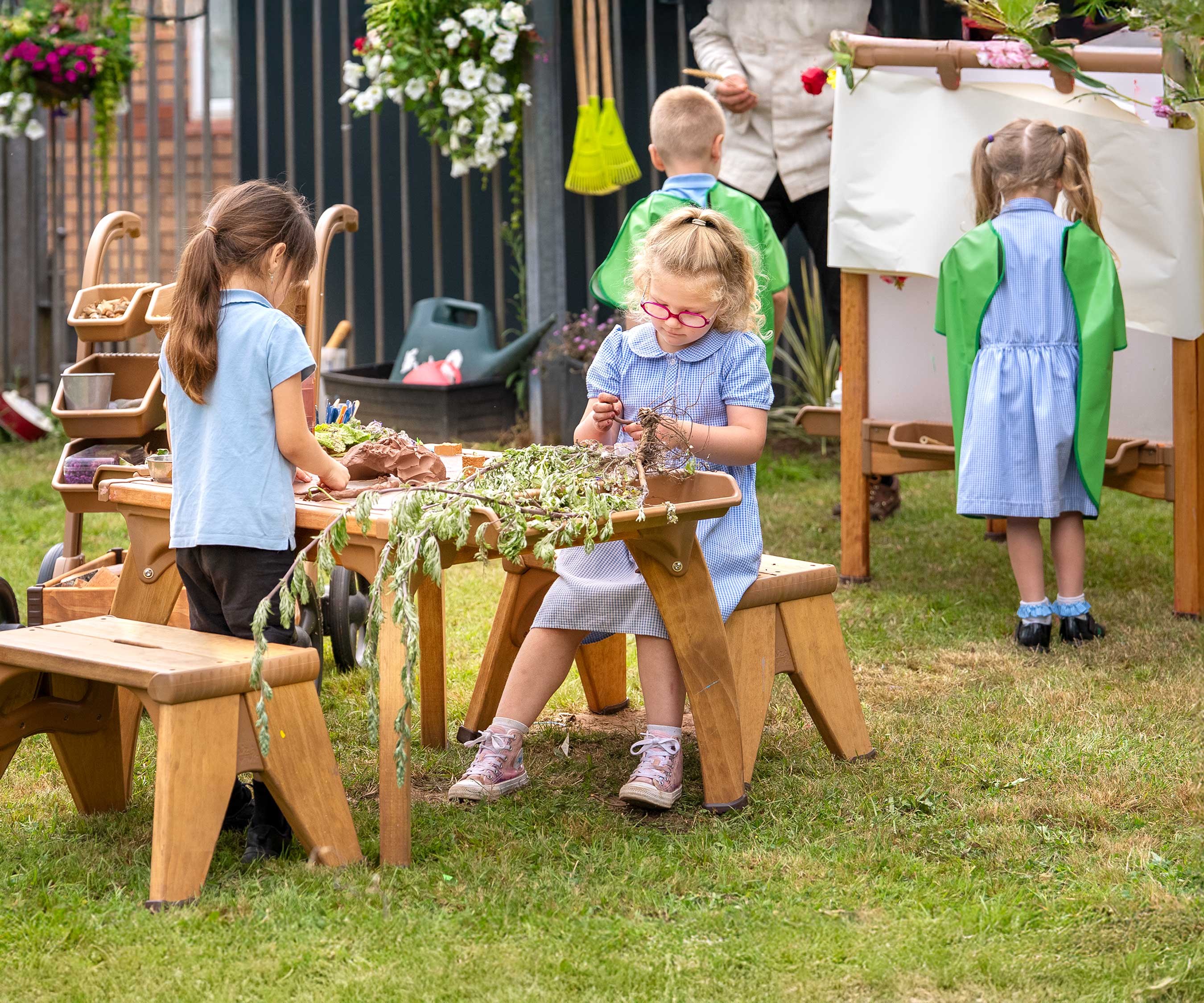 An outdoor art studio at a primary school with children working on art and science projects at an easel and art table.