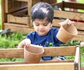 A young boy clips mud kitchen scoops onto a Carry crate