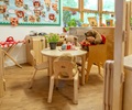 A home corner in a reception classroom set up with solid wood furniture and a round table